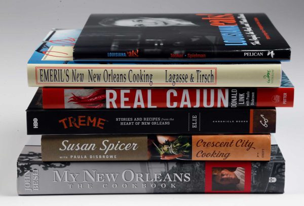 Stack of classic New Orleans cookbooks including Cajun and Creole recipe books showcasing Louisiana culinary traditions.