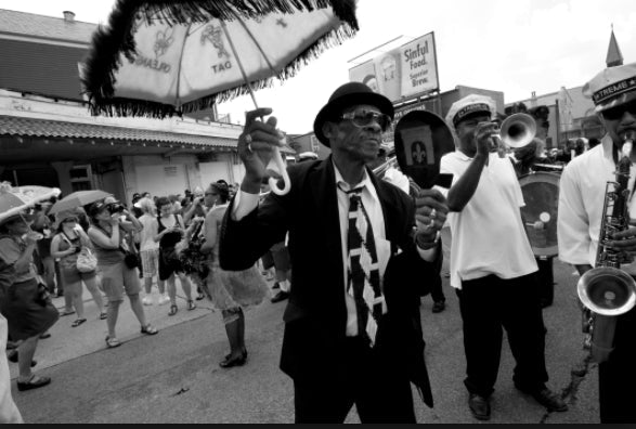 New Orleans second line parade with jazz band and participants dancing with umbrellas celebrating African American cultural tradition